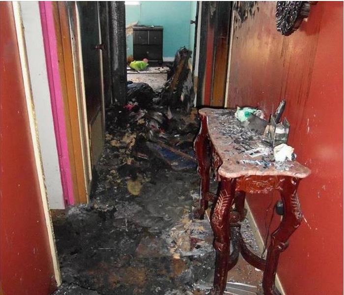 charred materials heaped in hallway, smoke damaged red walls